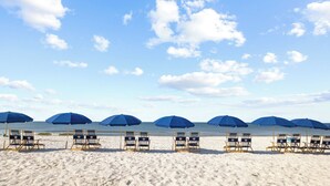 Een strand met rijen strandstoelen en parasols.