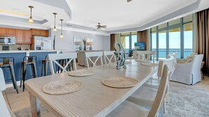 A spacious dining area with a wooden table, woven placemats, and modern chairs. - Phoenix West 1601 by Liquid Life (Orange Beach)