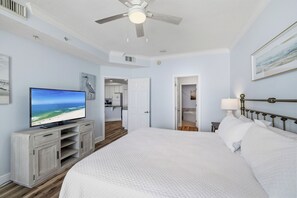 Une chambre avec un lit, une télévision, un ventilateur de plafond et une vue sur la plage.