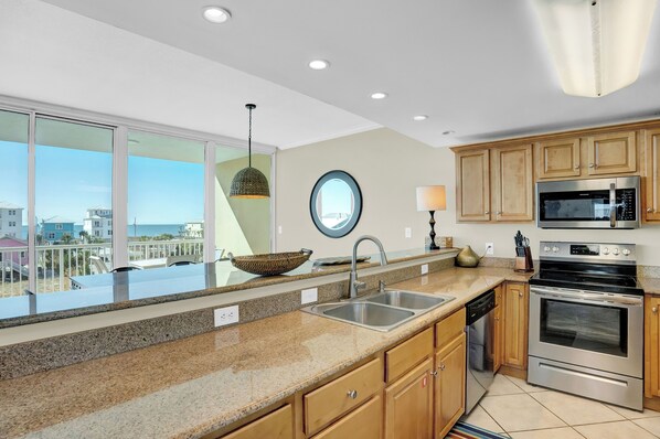 A modern kitchen with granite countertops, stainless steel appliances, and wooden cabinets. - Sanibel 307 by Liquid Life (Gulf Shores)