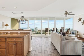 A spacious kitchen with a large island, a dining area with a view, and a balcony with outdoor furniture. - Sanibel 501 by Liquid Life (Gulf Shores)