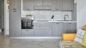 A modern kitchen with grey cabinetry, a built-in oven, a sink, and a small potted plant.