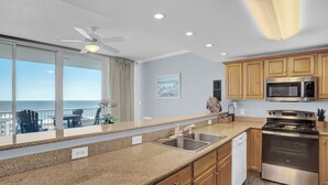 Una cocina con vista al océano, un ventilador de techo y armarios de madera.