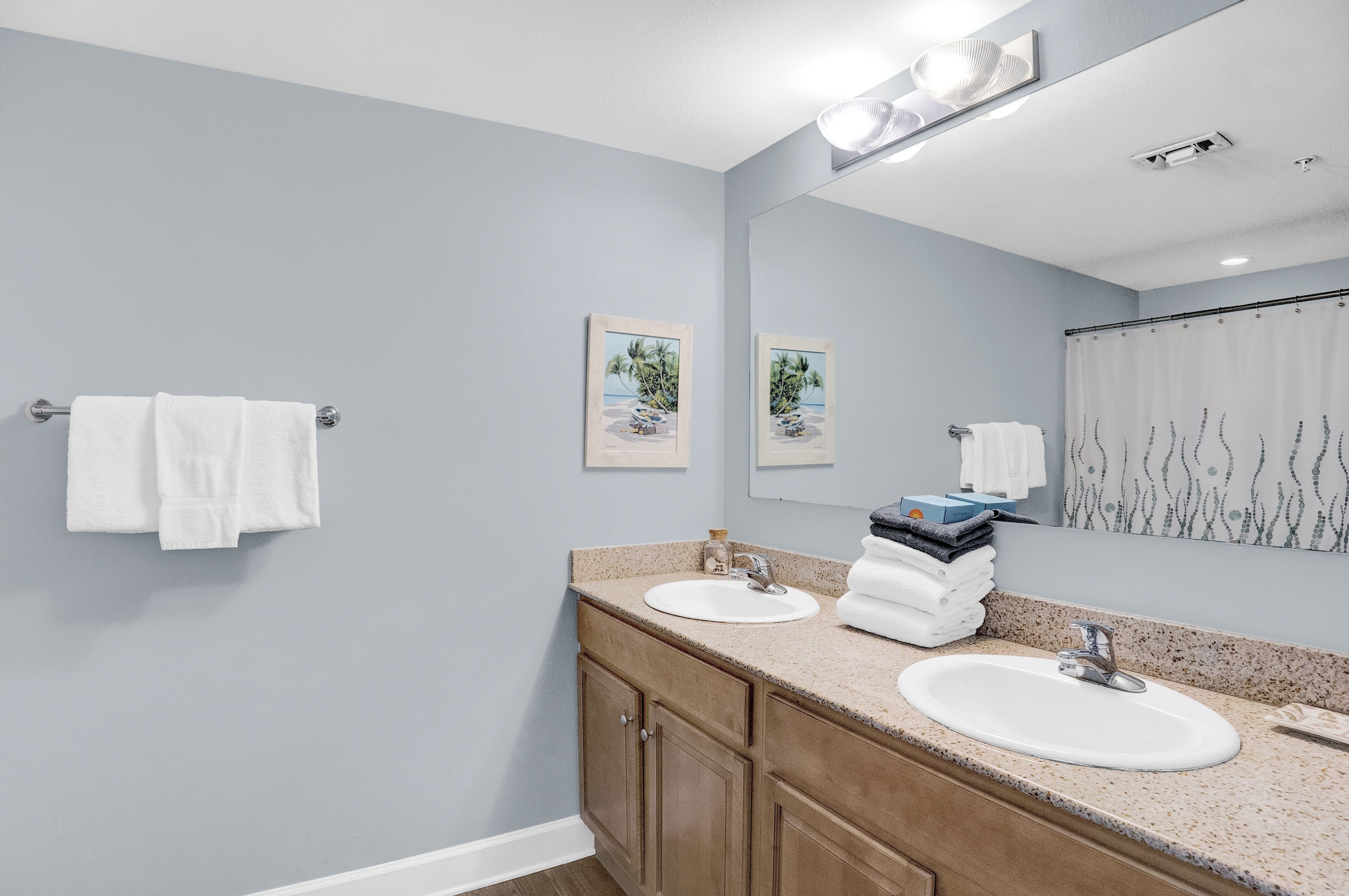 A bathroom with two sinks, a mirror, and towels on a rack.
