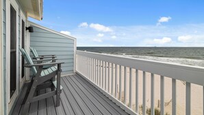 Eine Holzterrasse mit Geländer, die auf einen Strand blickt.