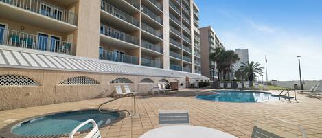 A hotel with multiple balconies, a swimming pool, and outdoor seating.