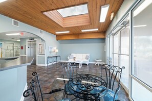 A spacious room with a high ceiling, a skylight, a seating area with a sofa and chairs, and a counter.