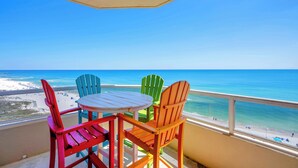 Ein Balkon mit Tisch und vier Stühlen mit Blick auf einen Strand.