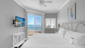 Ein Schlafzimmer mit einem großen Bett, einem Deckenventilator, einem Fernseher und Blick auf den Ozean.