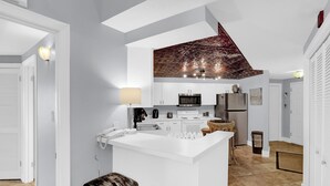 A modern kitchen with white cabinetry, a central island, and a unique ceiling design. - The Palms 313 by Liquid Life (Orange Beach)