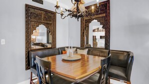 A dining area with a wooden table, black leather chairs, and ornate wall mirrors. - The Palms 313 by Liquid Life (Orange Beach)