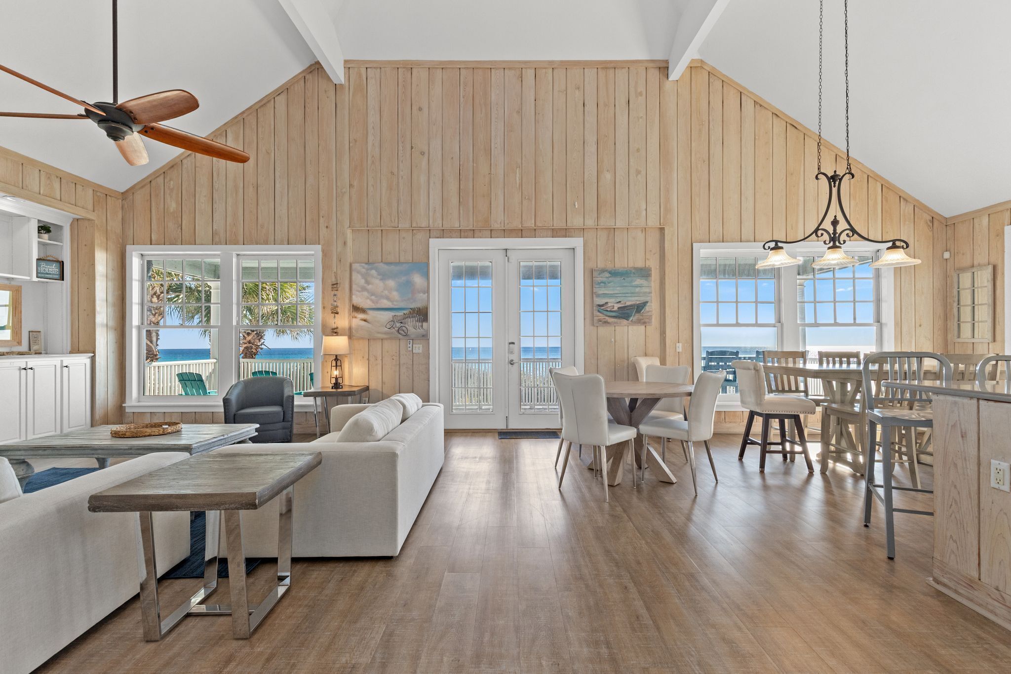 A spacious living area with a high ceiling, wooden walls, and a view of the ocean.