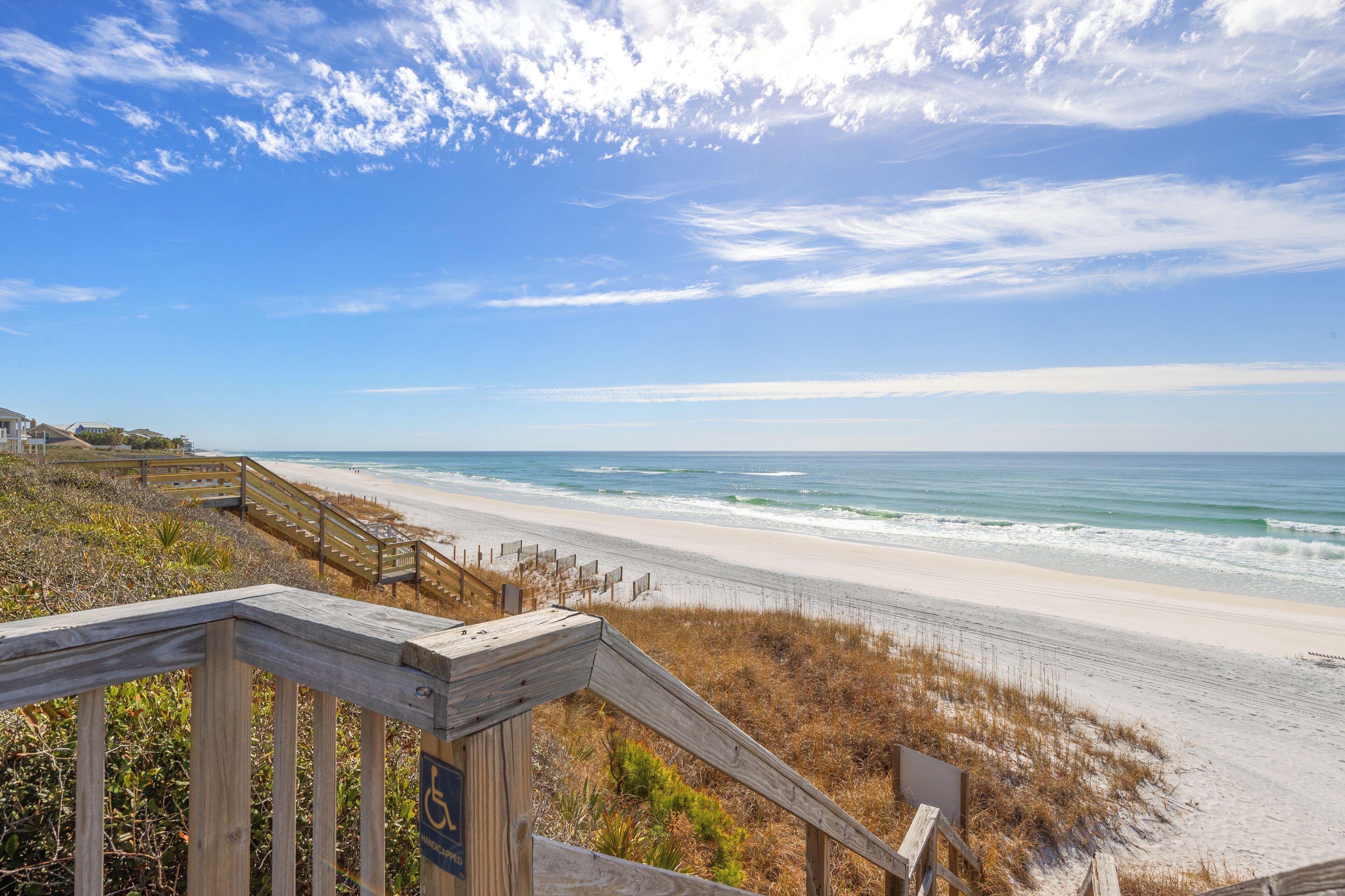 A wooden boardwalk leading to a beach with a clear view of the ocean.