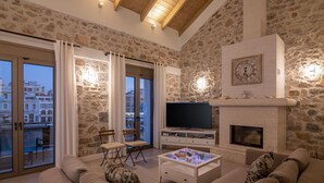 Una sala de estar con paredes de piedra, chimenea, televisor y sofá.
