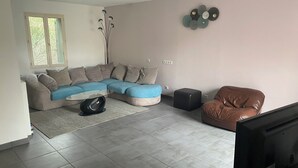 A living room with a sectional sofa, a coffee table, a brown leather chair, and a decorative wall piece.
