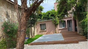 A modern house with a wooden deck, a small garden, and a stone wall.
