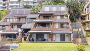 A multi-story residential building with a prominent balcony, a small patio area, and a sign indicating the address. - A Yachtsman Rest, 3-37 Victoria Pde - stunning unit with stunning views (Nelson Bay)