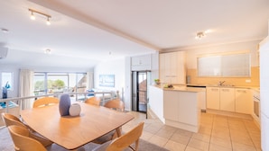 A modern apartment with a dining area, kitchen, and balcony. - A Yachtsman Rest, 3-37 Victoria Pde - stunning unit with stunning views (Nelson Bay)