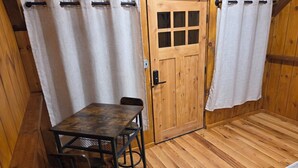 A wooden room with a table and chairs, a door with a window, and a curtain. - Lazy T Cabins - Grand Teton (Graham County)