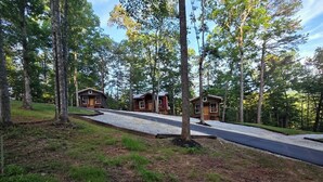 A cabin with a paved driveway and a wooden deck, surrounded by trees. - Lazy T Cabins - Grand Teton (Graham County)