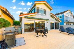 A modern two-story house with a patio area featuring a grill, outdoor seating, and a view of the cityscape. - On The Water! Channel Islands Harbor, Private Spa (Oxnard)