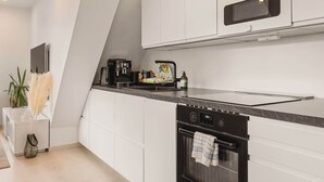 Eine moderne Küche mit weißen Schränken, einer schwarzen Arbeitsplatte und einem eingebauten Backofen.