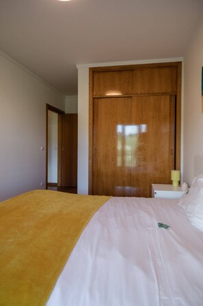 Une chambre à coucher avec un lit, une armoire en bois et une table de chevet avec une lampe.