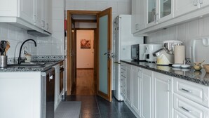 A modern kitchen with white cabinets, a granite countertop, and a central island. - Gaia Beach&Golf – EcoHost | Parking · Surf · 5 pax (Arcozelo)
