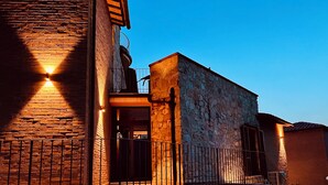 Un edificio con fachada de piedra, un balcón y una escalera que conduce a la entrada.