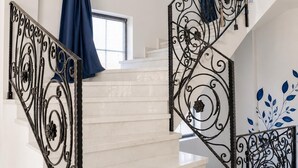 Eine Treppe mit weißen Marmorstufen und schwarzen schmiedeeisernen Geländern.