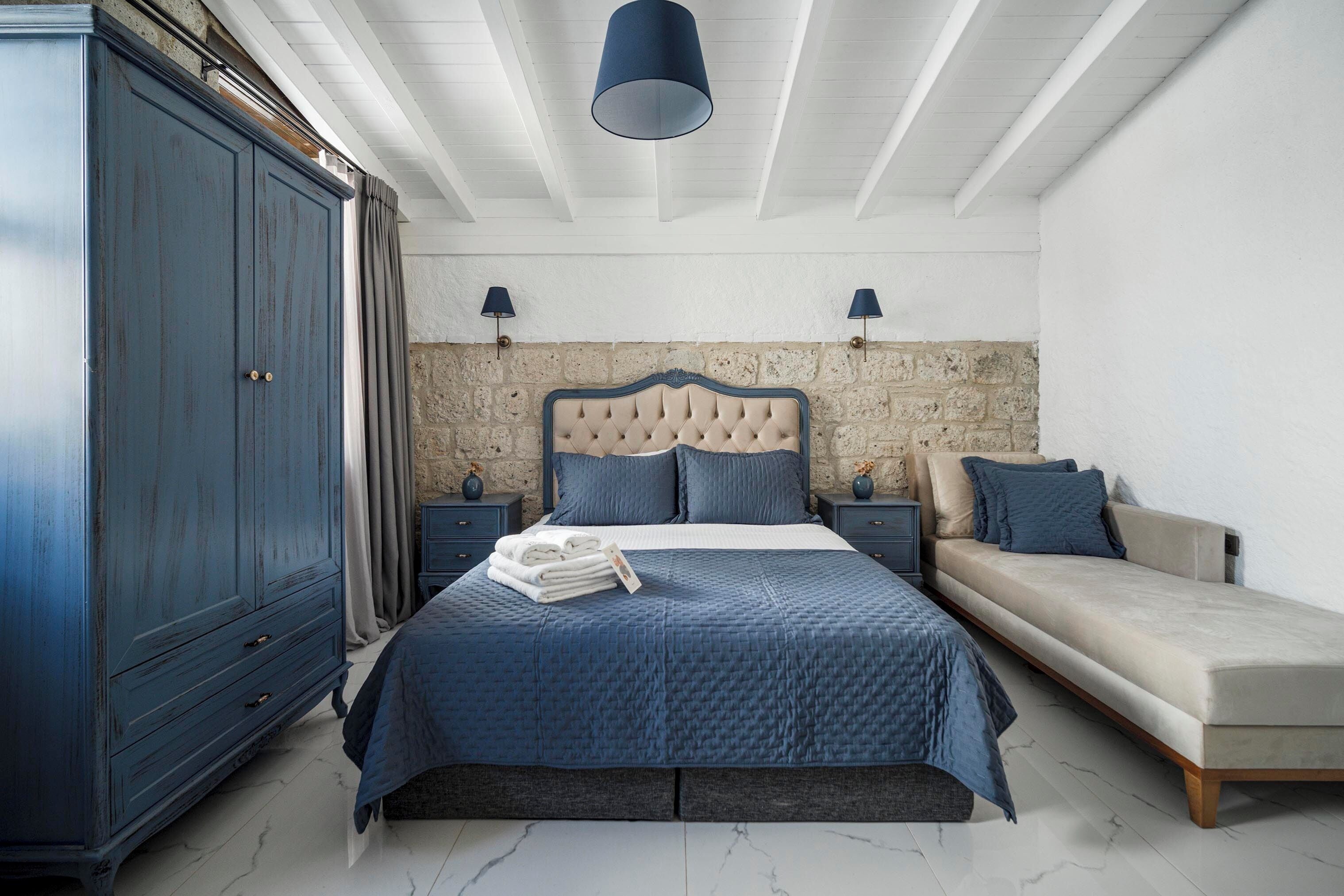 Un dormitorio con una cama grande, una mesita de noche, un aparador y un sofá.