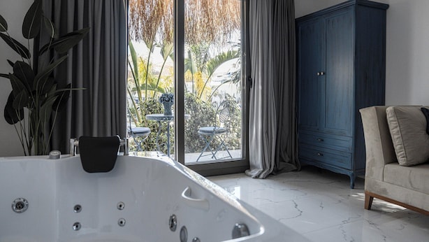 Ein modernes Badezimmer mit einer freistehenden Badewanne, einem dunkelblauen Kleiderschrank und Blick ins Freie durch eine Glastür.