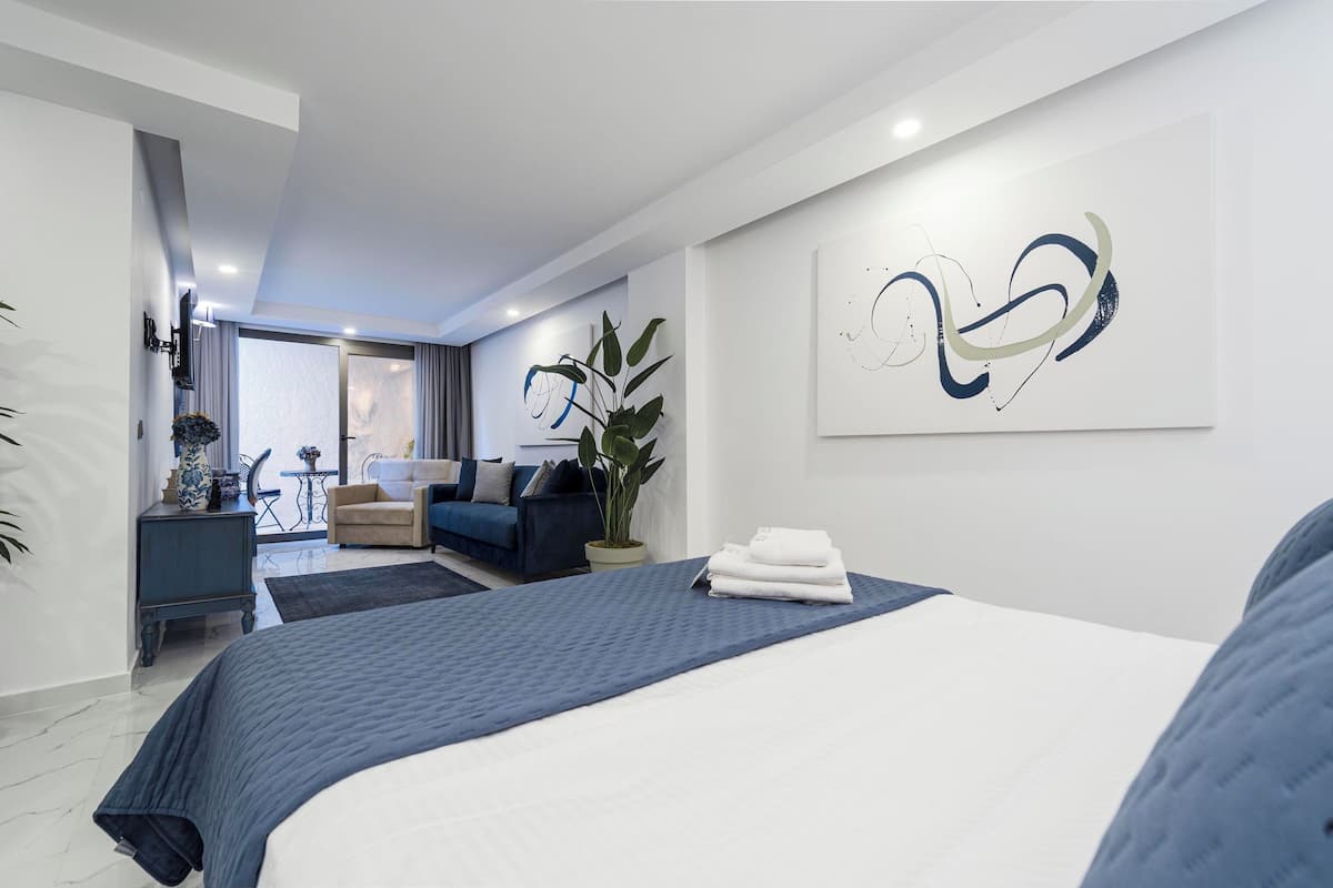 Ein modernes Hotelzimmer mit einem großen Bett, einer Couch, einem Schreibtisch und einer Zimmerpflanze.