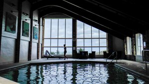 Une piscine avec vue sur le ciel grâce à de grandes fenêtres, une statue et une horloge murale.