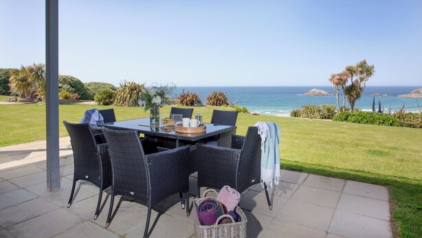 Une terrasse extérieure avec une table et des chaises, offrant une vue sur la côte.