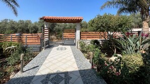 Un espacio de estar al aire libre cubierto con piso de baldosas, bancos y una pérgola.