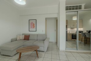 Una sala de estar moderna con un sofá gris, una mesa de centro de madera y una obra de arte enmarcada en la pared.