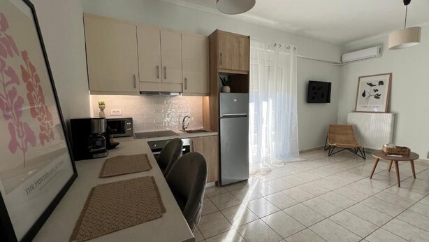 Una cocina moderna con armarios de colores claros, un refrigerador y un comedor con mesa y sillas.