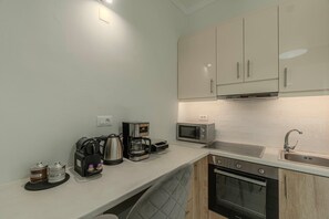 Una cucina moderna con mobili bianchi, un forno a microonde, una macchina da caffè e un bollitore.