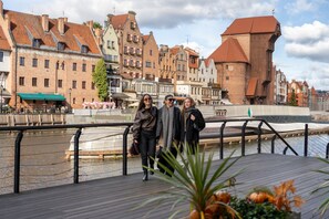 A wooden boardwalk with a river and historic buildings in the background. - Riverside Nadmotławie - Sauna, Gym & Kids Play by Lion Apartments (Gdansk)