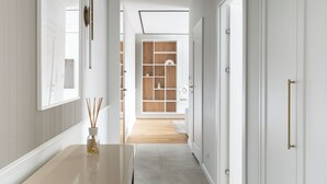 A hallway with a wooden floor, white walls, and a door leading to a room with a wooden cabinet. - Riverside Nadmotławie - Sauna, Gym & Kids Play by Lion Apartments (Gdansk)