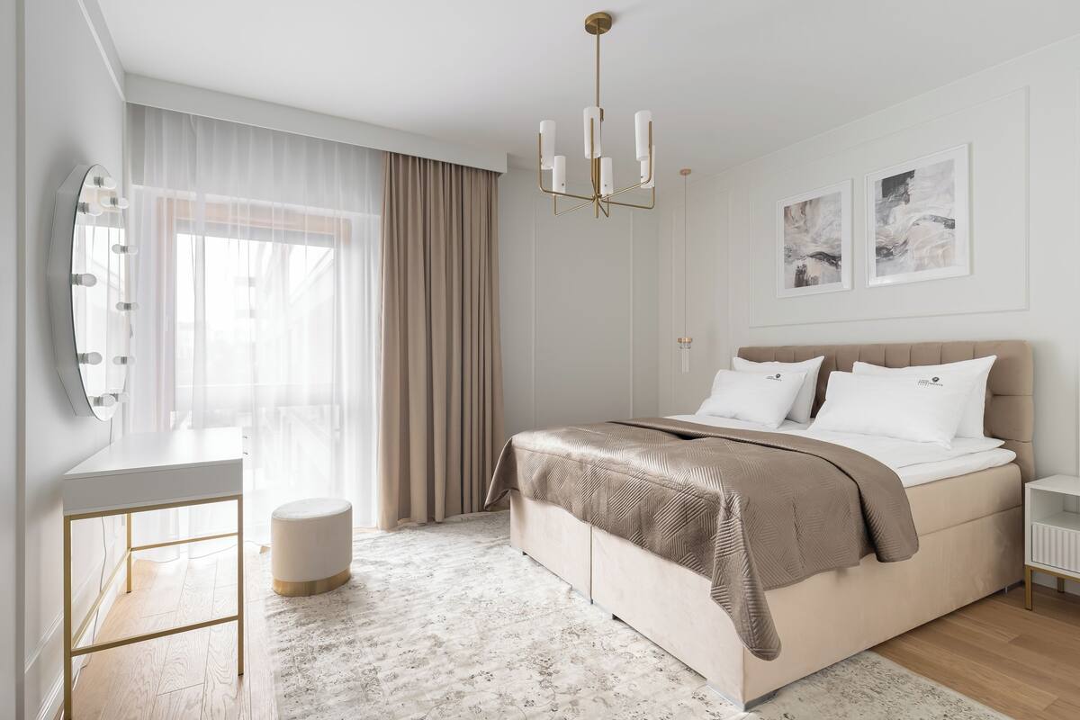 Ein modernes Schlafzimmer mit einem großen Bett, einem Schminktisch mit Spiegel und einer Kristallleuchtre.