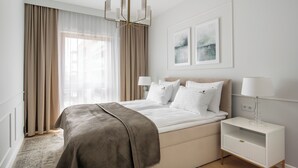 A modern bedroom with a large bed, bedside lamps, a nightstand, and artwork on the wall. - Riverside Nadmotławie - Sauna, Gym & Kids Play by Lion Apartments (Gdansk)