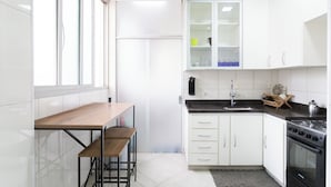 Een moderne keuken met witte kasten, een houten tafel en een zwart fornuis.