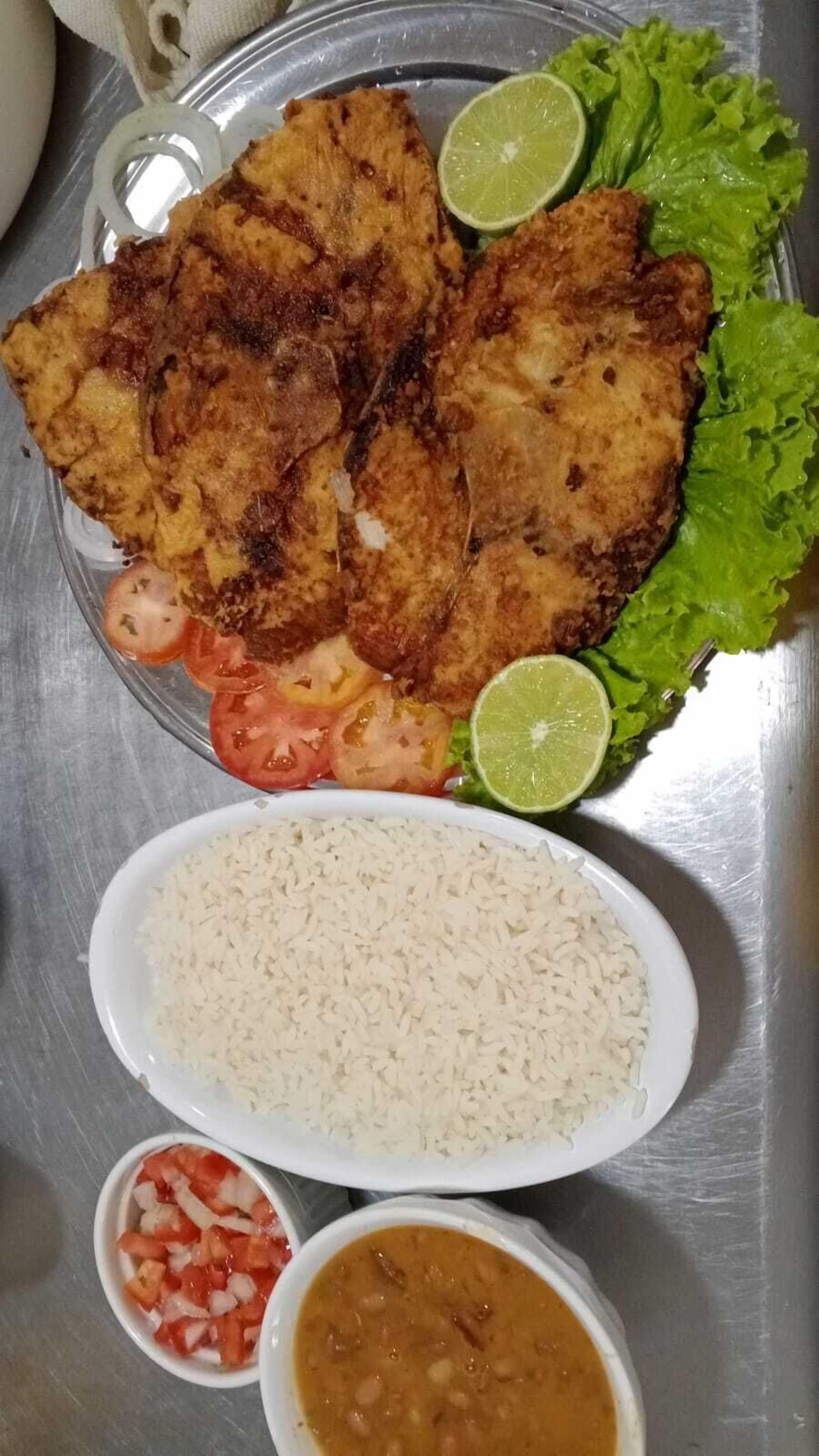 A plate with fried fish, rice, and a side of sauce.