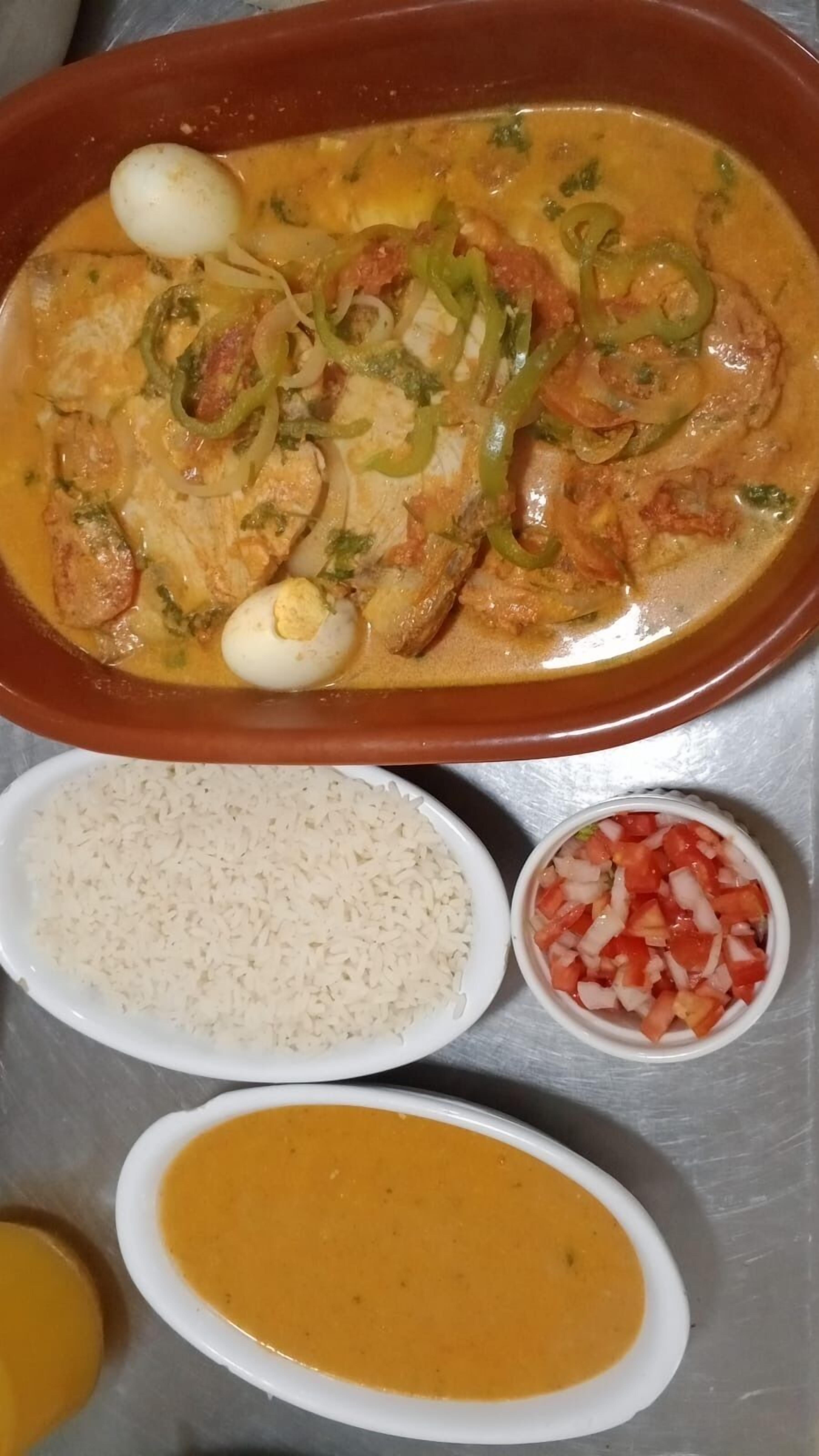 A meal consisting of a curry with vegetables and a boiled egg, served with white rice and a side of diced tomatoes.
