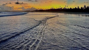 Une plage avec des vagues et un coucher de soleil.