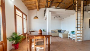 A spacious living area with a wooden dining table, chairs, a sofa, and a ladder. - Casa Tharros in Nurachi (Nurachi)