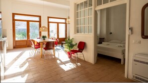 A bright, open-plan living space with a dining area, a bed, and large windows. - Casa Tharros in Nurachi (Nurachi)