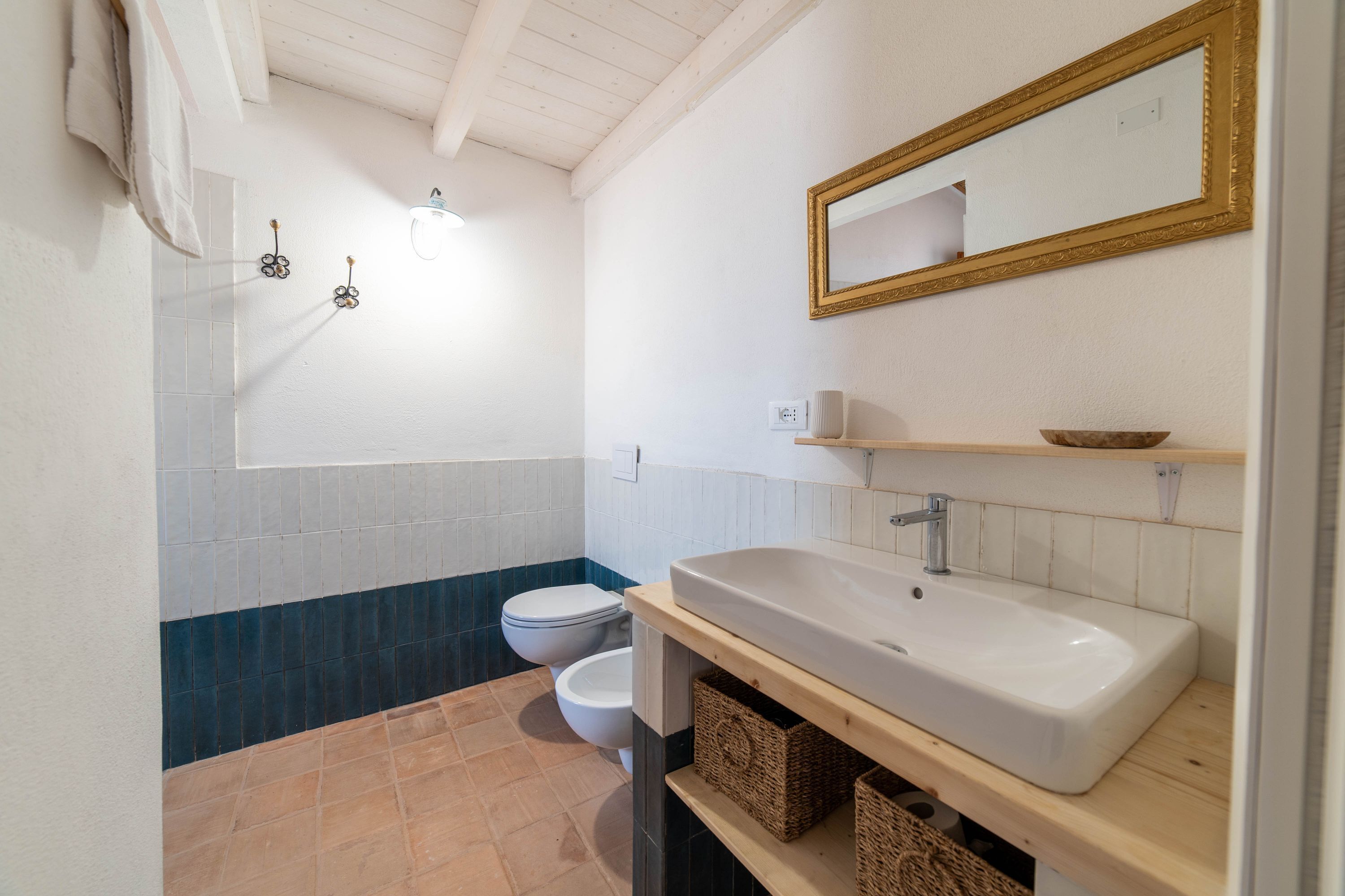 A bathroom with a white sink, a mirror, a toilet, and a towel hanging on the wall.
